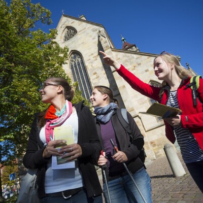 Touristinnen mit Rucksack und Wanderstöcken vor der Stadtkirche 