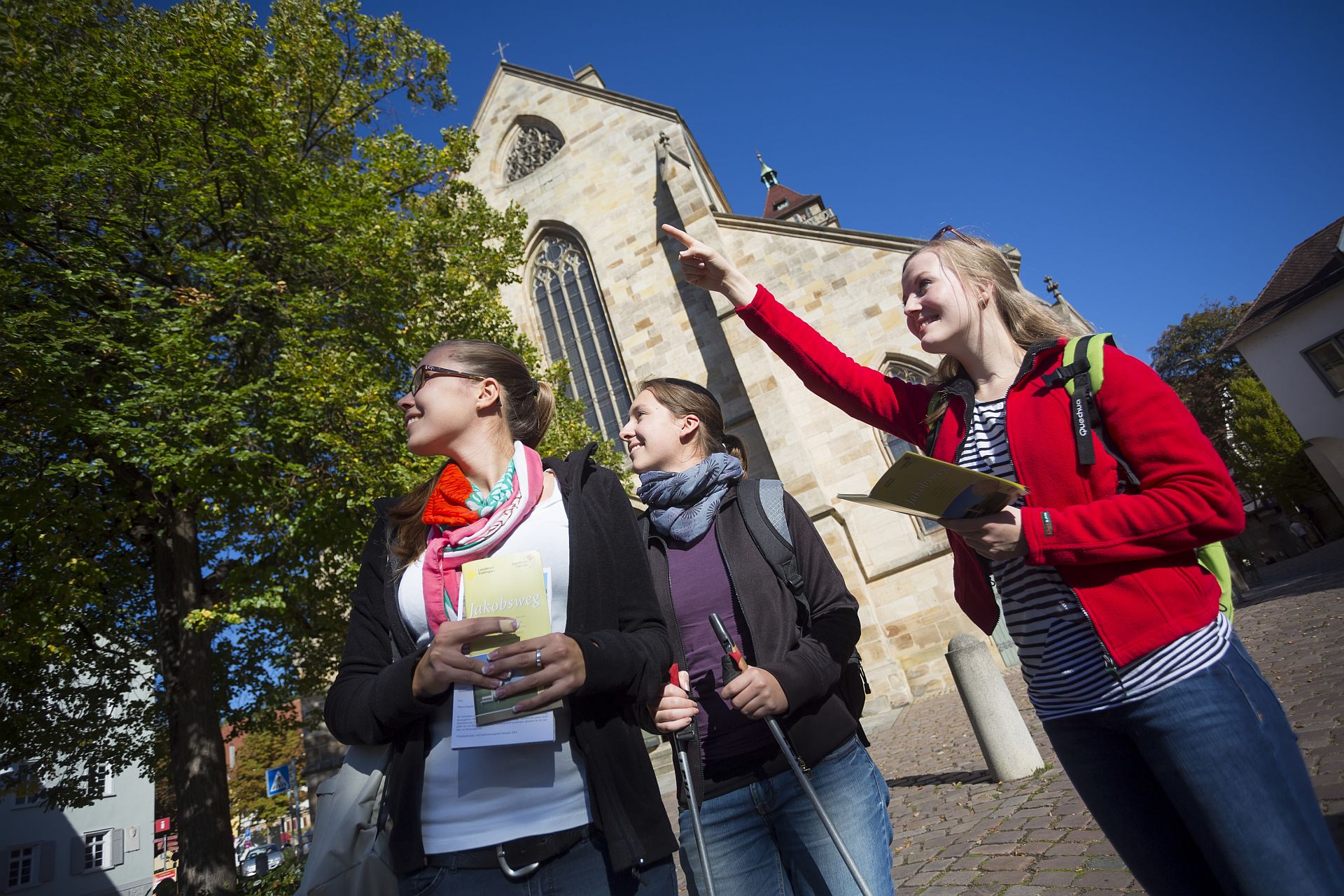 Touristinnen mit Rucksack und Wanderstöcken vor der Stadtkirche